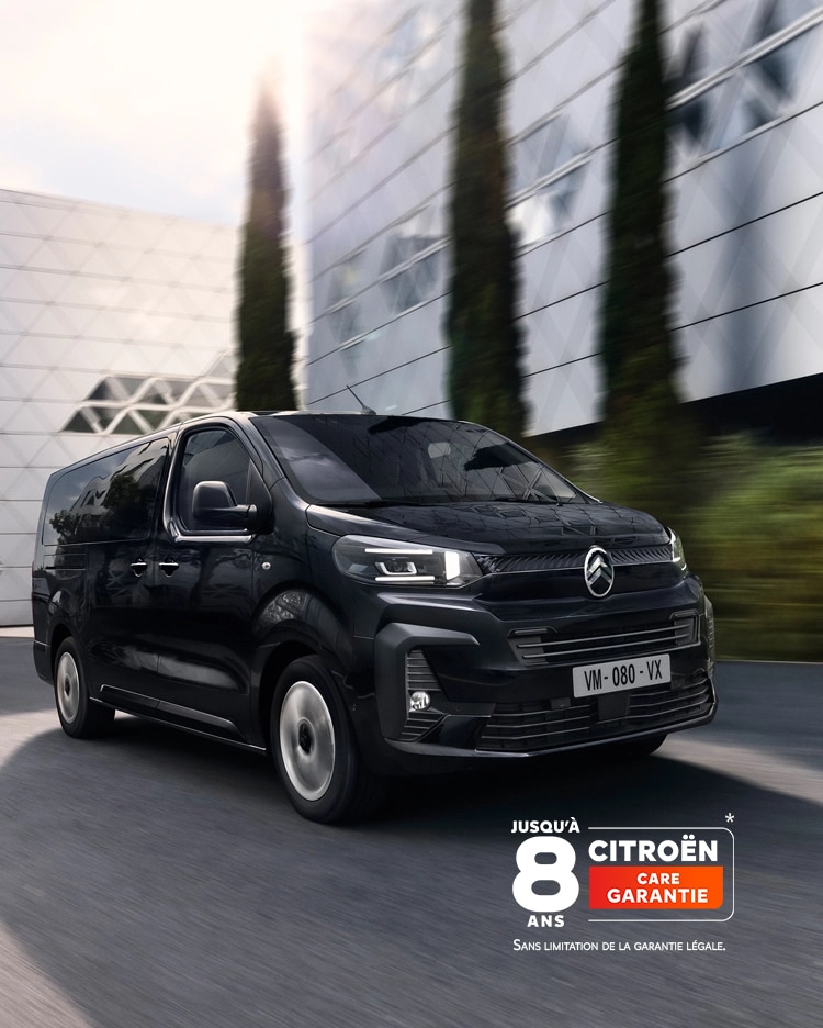 Vue frontale des trois quarts de la Citroën ë-SpaceTourer circulant en zone urbaine, mettant en valeur son design électrique moderne